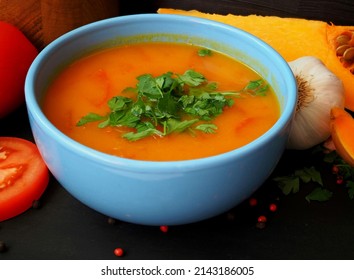 A plate of Vedic pumpkin soup. Serving with fresh tomatoes and herbs. Close-up