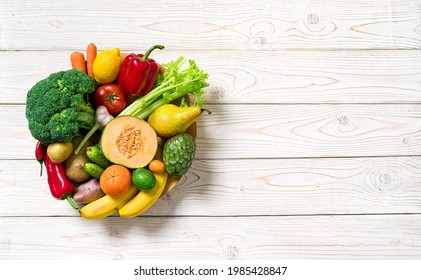 Plate with vegetables and fruits on wooden table. Healthy food, top view. - Shutterstock ID 1985428847