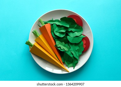 Plate With Vegetables Made From Paper: Carrots, Tomato, Spinach And Arugula On Blue Background. Minimal, Creative, Vegan, Healthy Or Food Art Concept. Copy Space. Top View