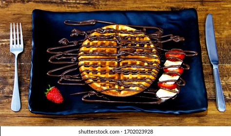 A Plate Of Waffle With Nutella And Fruits