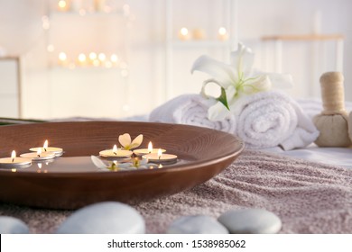 Plate With Water And Candles On Towel In Beauty Center