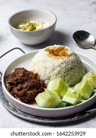 A plate of white rice with rendang, cucumber and tofu soup.