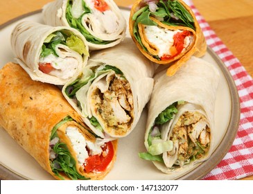 Plate of wrap sandwiches filled with chicken and cheese.