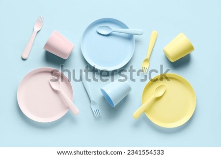 Plates with cups and cutlery for baby on blue background