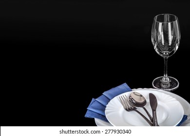 plates and cutlery with blue napkin and empty glass isolated on black - Powered by Shutterstock