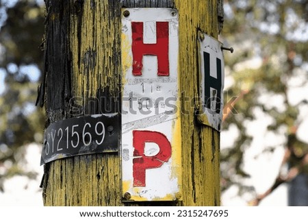 Plates on yellow timber power line pole with red HP -hydrant in pathway- and green H -hydrant marker around the pole- letters. Corner of Liverpool St and Barcom Ave, Darlinghurst. Sydney-NSW-Australia
