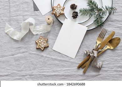 Plates, Pine Cones On Table Cloth. Winter Festive Greeting Cards Mockup Scene. Golden Cutlery,gingerbread Cookies And Fir Tree Branches. Christmas Table Setting, Holiday Background. Flat Lay, Top View