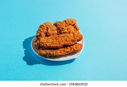 Plates In The Shape Of A Heart With Nuggets, Wings And Strips On Blue Background With Long Shadows In Minimal Style. Fast Food, Junk Food. Top View. Minimal Style. Pop Art Design, Creative Concept