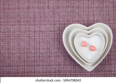 Plates with the shape of a heart and two sweets on a pink background. Valentine's Day. 