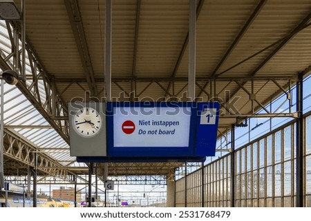 Platform information display with clock. Sign: do not board.  Dutch central railway or train station. Netherlands, part of a serie.