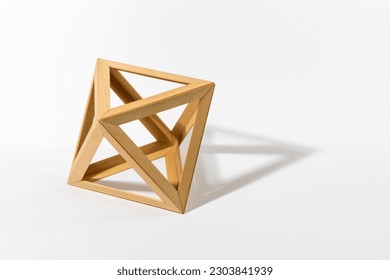 Platonic solid octahedron shape made of wooden parts casting shadow on gray background