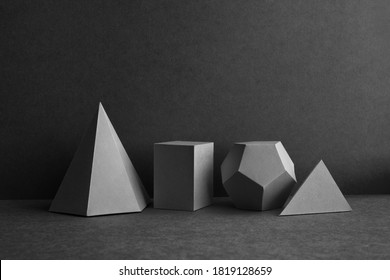 Platonic solids figures geometry. Abstract geometrical figures still life composition. Three-dimensional prism pyramid cube objects on black gray background