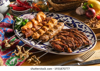 Platter of kebabs. Uch-panzha of lamb, kebab chicken kebab with lamb, a shish kebab of chicken and lamb skewers on a plate with traditional Uzbekistan ornament.