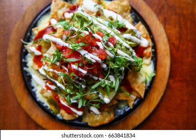 Platter of Mexican Nachos with Tortilla Chips, Sour Cream, Cheese, Salsa and Vegetables