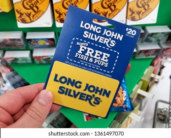 PLATTSBURGH, USA - JANUARY 21, 2019 : Long John Silvers Gift Card In A Hand Over A Shelves With Different Giftcards In A Walmart Store.