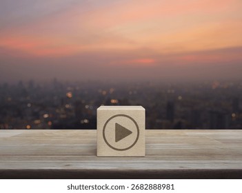 Play button flat icon on wood block cube on wooden table over blur of cityscape on warm light sundown, Business music online concept
