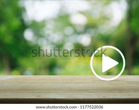 Play button flat icon on wooden table over blur green tree in park, Business music online concept