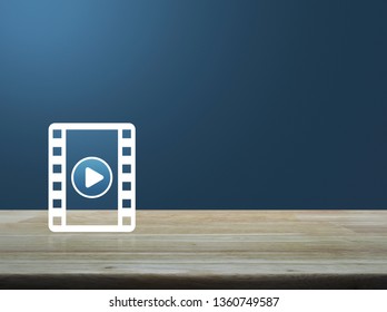 Play button with movie flat icon on wooden table over light blue gradient background, Business cinema online concept - Powered by Shutterstock