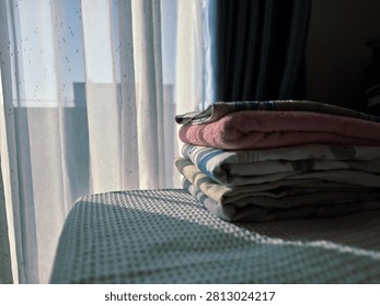 The play of light and shadow highlights the textures of the fabric, turning a simple household chore into a serene aesthetic moment.