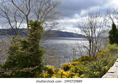 Play of light and shadow on the darkening clouds over Loch Ness lake in Scotland. Where the light hits, the greenery is lighter in colour while the other shore is in shadow.