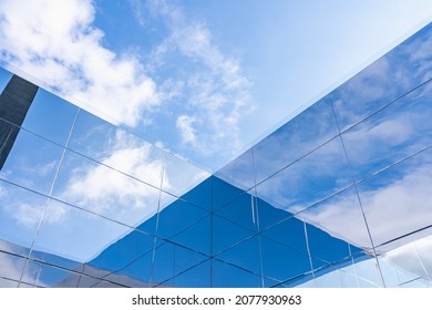 The play of light and shadow on the mirrored surfaces of a modern building. Blue sky in the clouds and its reflection