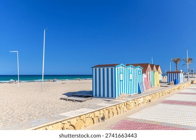 Playa de San Juan beach in Alicante city Campello town embankment, colorful striped bathing huts cabins on Muchavista sandy beach of Mediterranean Sea coast Costa Blanca in sunny summer day, Spain