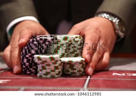 Player at gambling table pusing large stack of chips