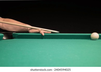 a player hits a white ball on the billiard table with a cue. playing billiards while relaxing in the pub.