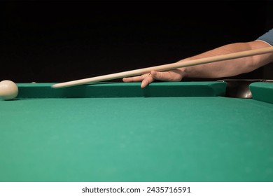 a player hits a white ball on the billiard table with a cue. playing billiards while relaxing in the pub.