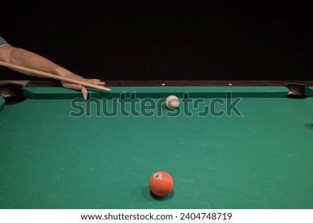a player hits a white ball on the billiard table with a cue. playing billiards while relaxing in the pub. copy space.