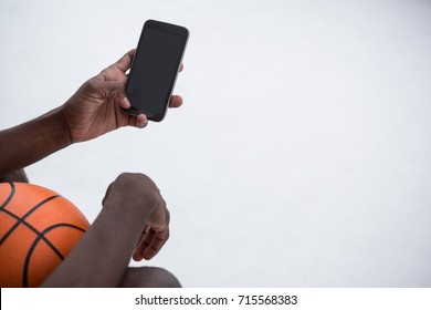 Player holding basketball while using mobile phone on terrace - Powered by Shutterstock