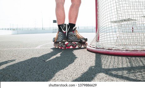 
The player in the inline skates stands at his gate. Before the big tournament. Empty ice hockey playground - view from behind the gate. Before The Match On Top Of Street Hockey.