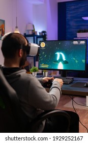 Player Man Playing Video Game At Powerful Computer Late Night Wearing Vr Headset. Excited Player Using Wireless Controller For Virtual Tournament Gaming Space Shooter At Home