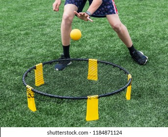 A Player Is Playing Spike Ball On A Green Turf Field.