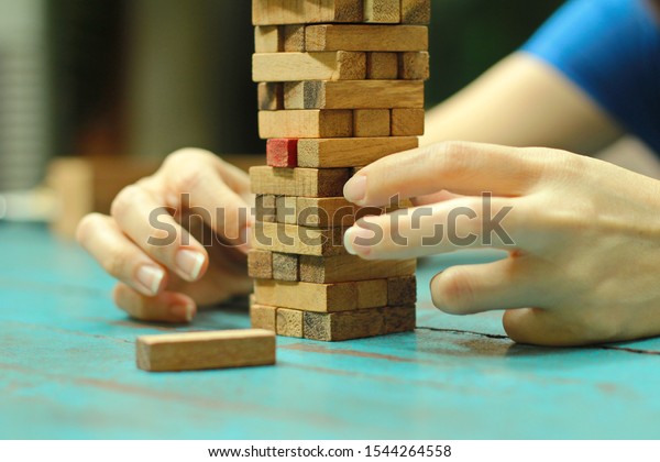 Player removing block from Jenga tower constructed \
Toy Block, Brick, Human Hand, Toy, Block Removal Game ,block wood\
jenja