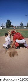 Player Sliding Towards The Home Plate To Complete A Run With Goalkeeper On The Field