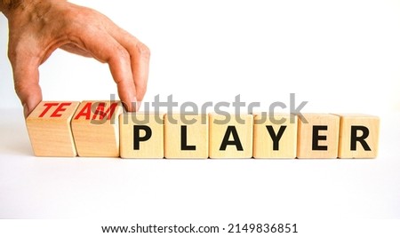 Player or teamplayer symbol. Businessman turns wooden cubes and changes concept words Player to Teamplayer. Beautiful white table white background, copy space. Business player or teamplayer concept.
