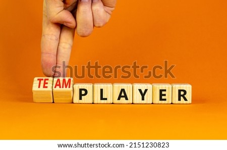 Player or teamplayer symbol. Businessman turns wooden cubes and changes concept words Player to Teamplayer. Beautiful orange table orange background, copy space. Business player or teamplayer concept.