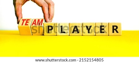 Player or teamplayer symbol. Businessman turns wooden cubes and changes concept words Player to Teamplayer. Beautiful yellow table white background, copy space. Business player or teamplayer concept.