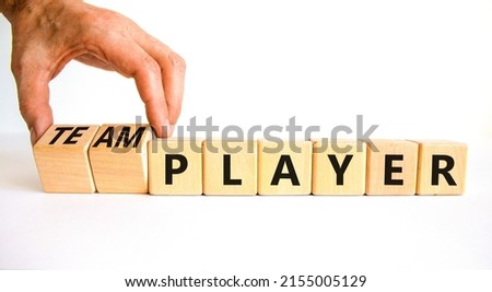 Player or teamplayer symbol. Businessman turns wooden cubes and changes concept words Player to Teamplayer. Beautiful white table white background, copy space. Business player or teamplayer concept.