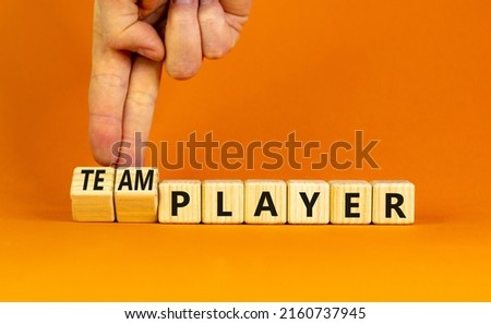 Player or teamplayer symbol. Businessman turns wooden cubes and changes concept words Player to Teamplayer. Beautiful orange table orange background, copy space. Business player or teamplayer concept.