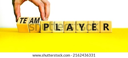 Player or teamplayer symbol. Businessman turns wooden cubes and changes concept words Player to Teamplayer. Beautiful yellow table white background, copy space. Business player or teamplayer concept.