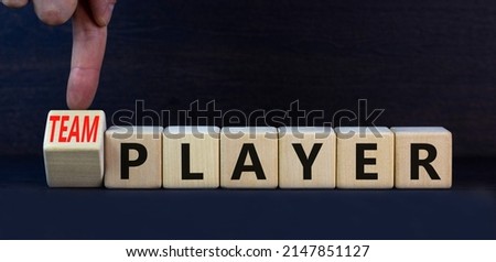 Player or teamplayer symbol. Turned wooden cubes and changed concept words Player to Teamplayer. Beautiful grey table grey background, copy space. Business player or teamplayer concept.