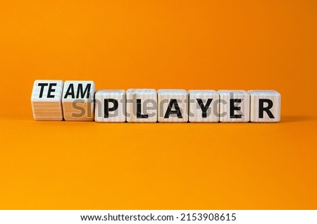 Player or teamplayer symbol. Turned wooden cubes and changed the concept word Player to Teamplayer. Beautiful orange table orange background, copy space. Business player or teamplayer concept.
