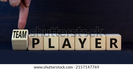 Player or teamplayer symbol. Turned wooden cubes and changed concept words Player to Teamplayer. Beautiful grey table grey background, copy space. Business player or teamplayer concept.