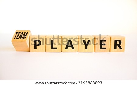 Player or teamplayer symbol. Turned wooden cubes and changed concept words Player to Teamplayer. Beautiful white table white background, copy space. Business player or teamplayer concept.