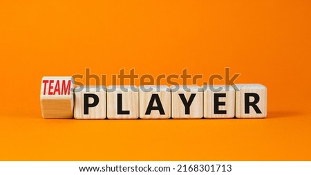 Player or teamplayer symbol. Turned wooden cubes and changed concept words Player to Teamplayer. Beautiful orange table orange background, copy space. Business player or teamplayer concept.