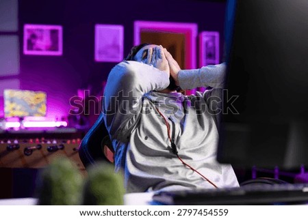 Player upset after losing while playing videogame, putting face in hands in frustration; gamer at computer desk feeling dejected after receiving game over screen, crying from anger.