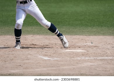 A player's feet as the hitter is poised and timed to the pitcher's throw during a baseball game.