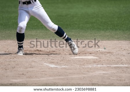 A player's feet as the hitter is poised and timed to the pitcher's throw during a baseball game.